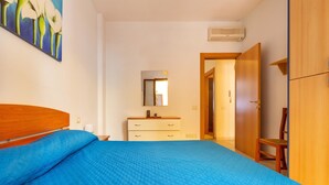 A bedroom with a bed, a dresser, a mirror, and a door leading to another room. - 1990 Appartamento Azzurra (Gallipoli)