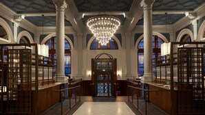 A grand lobby with a chandelier, arched windows, and a reception desk.