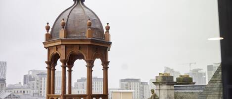 A domed structure with a weather vane, surrounded by urban buildings.