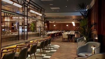 A restaurant with a bar area, multiple dining tables, and chairs.