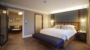 Una habitación de hotel moderna con una cama grande, un banco, un sofá y una mesa de comedor.