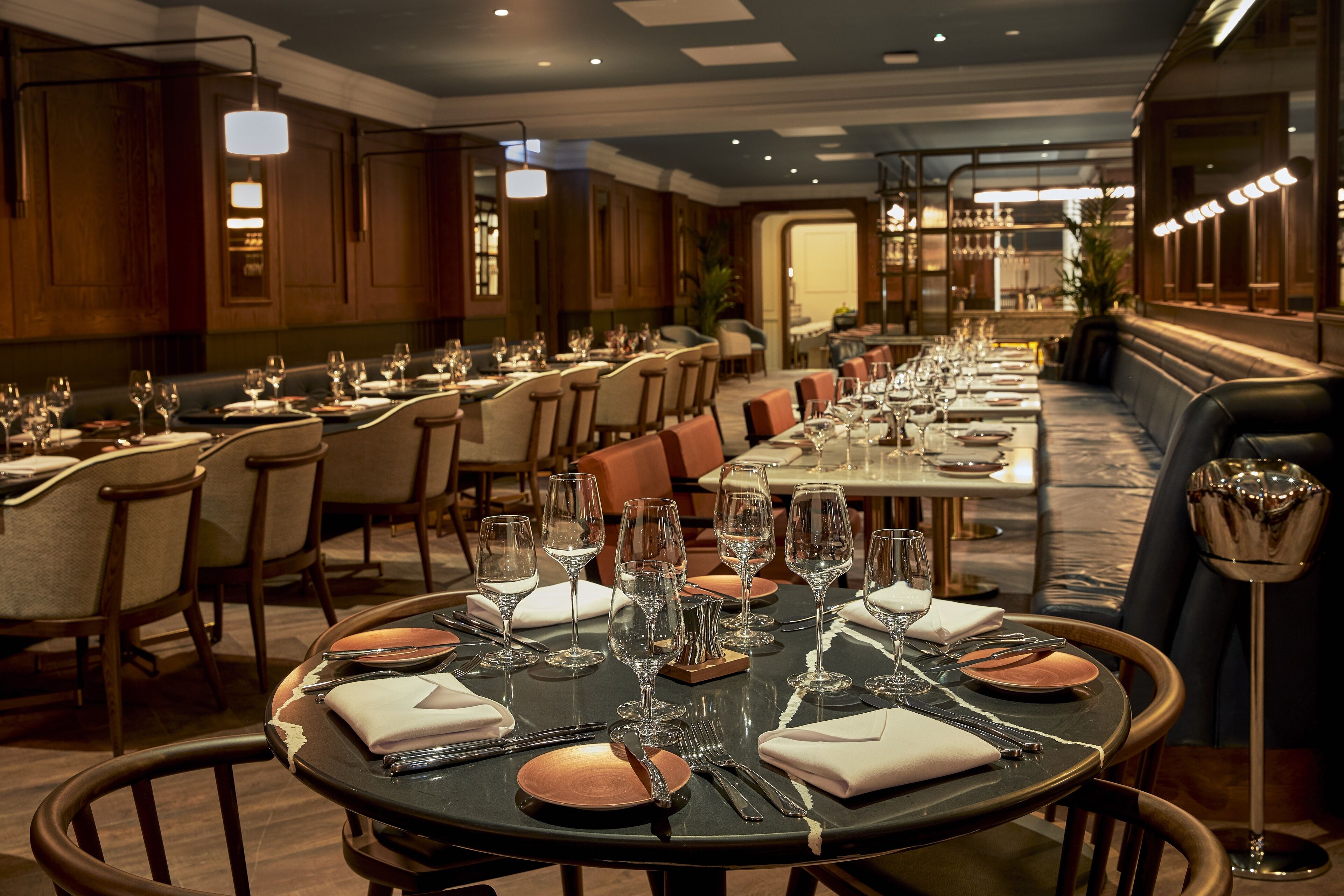 A restaurant with multiple dining tables set for service, each with chairs and a variety of tableware.