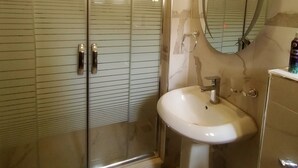 A bathroom with a glass-enclosed shower, a sink, and a mirror. - Nadi Paradise (Abuja)