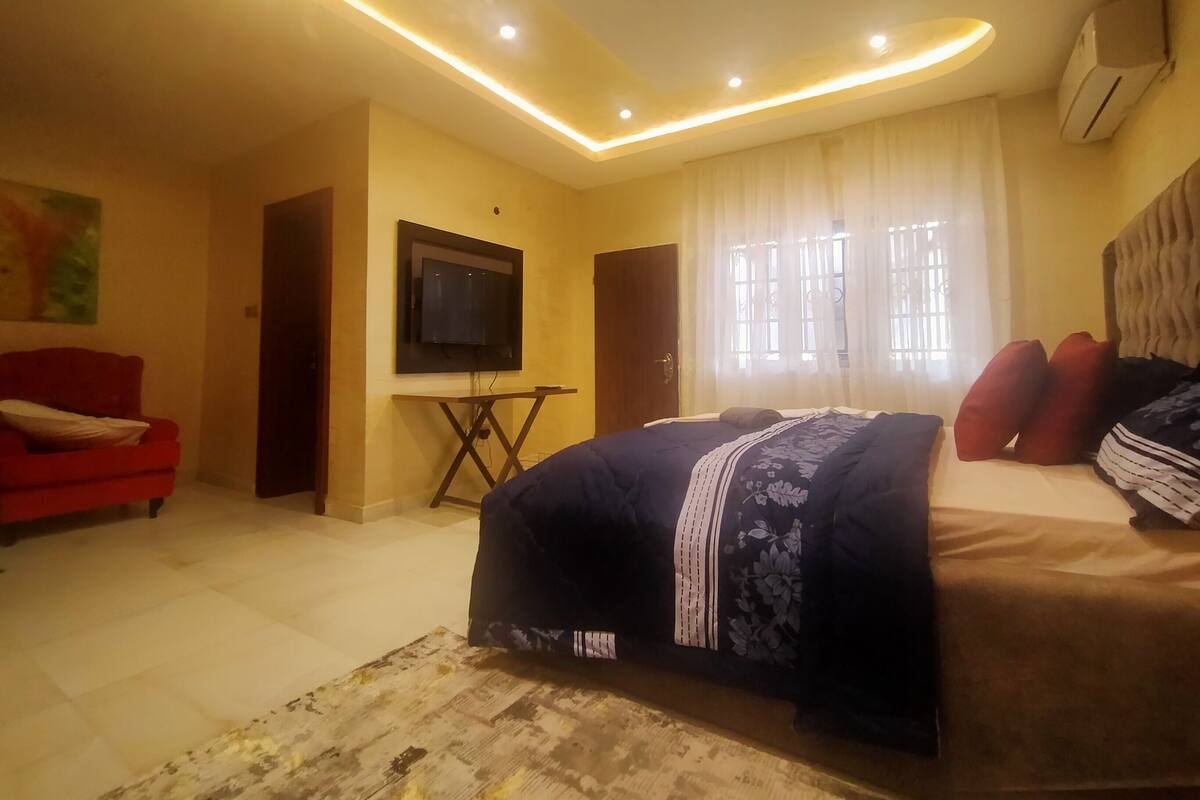 A bedroom with a bed, a TV, and a red armchair.