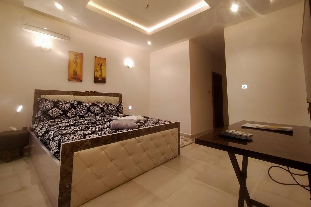 A modern bedroom with a bed, bedside table, and artwork on the wall.
