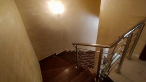 A wooden staircase with metal railings and a light fixture on the wall. - Nadi Paradise (Abuja)