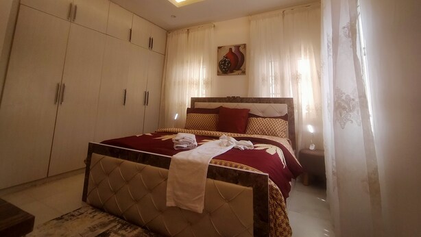 A bedroom with a bed, wardrobe, and a ceiling light fixture. - Nadi Paradise (Abuja)
