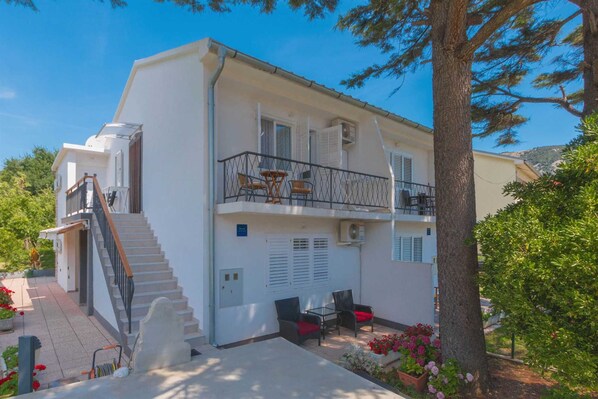 A two-story building with a balcony, outdoor seating, and a staircase leading to the upper floor.