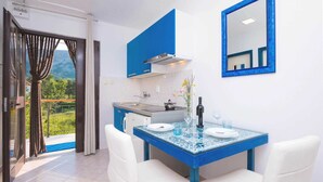 Una cocina moderna con armarios azules, una mesa de comedor de cristal y sillas blancas.