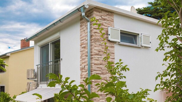 A modern two-story house with a stone facade, a balcony, and a small window with shutters. - Goran A2 - Cozy One-Bedroom Apartment with Parking Bliss for Two (Baška)