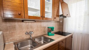 A kitchen with two stainless steel sinks, wooden cabinets, a green coffee maker, and a tiled backsplash. - Goran A2 - Cozy One-Bedroom Apartment with Parking Bliss for Two (Baška)