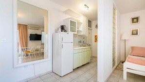 A compact kitchen with a refrigerator, a sink, and a microwave. There is a dining area with a chair and a table. - Dubravka, studio with sea view (Baška)