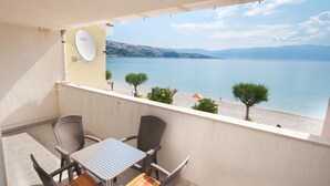 A balcony with a table and chairs, a satellite dish, and a view of a beach and water. - Dubravka, studio with sea view (Baška)