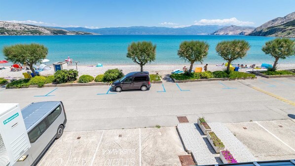 A parking lot with a car, a camper van, and a row of trees.