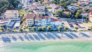 An aerial view of a coastal residential area with buildings, a beach, and a parking lot. - Dubravka, studio with sea view (Baška)