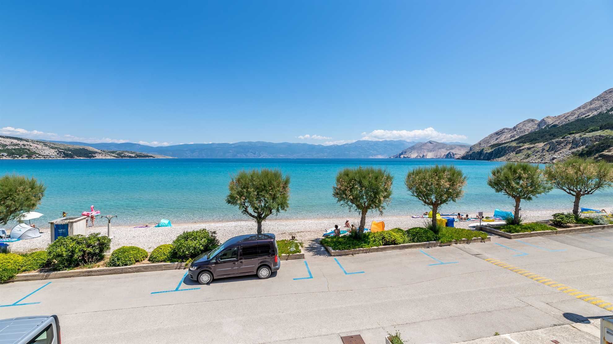 A parking area with a view of a beach and the sea.