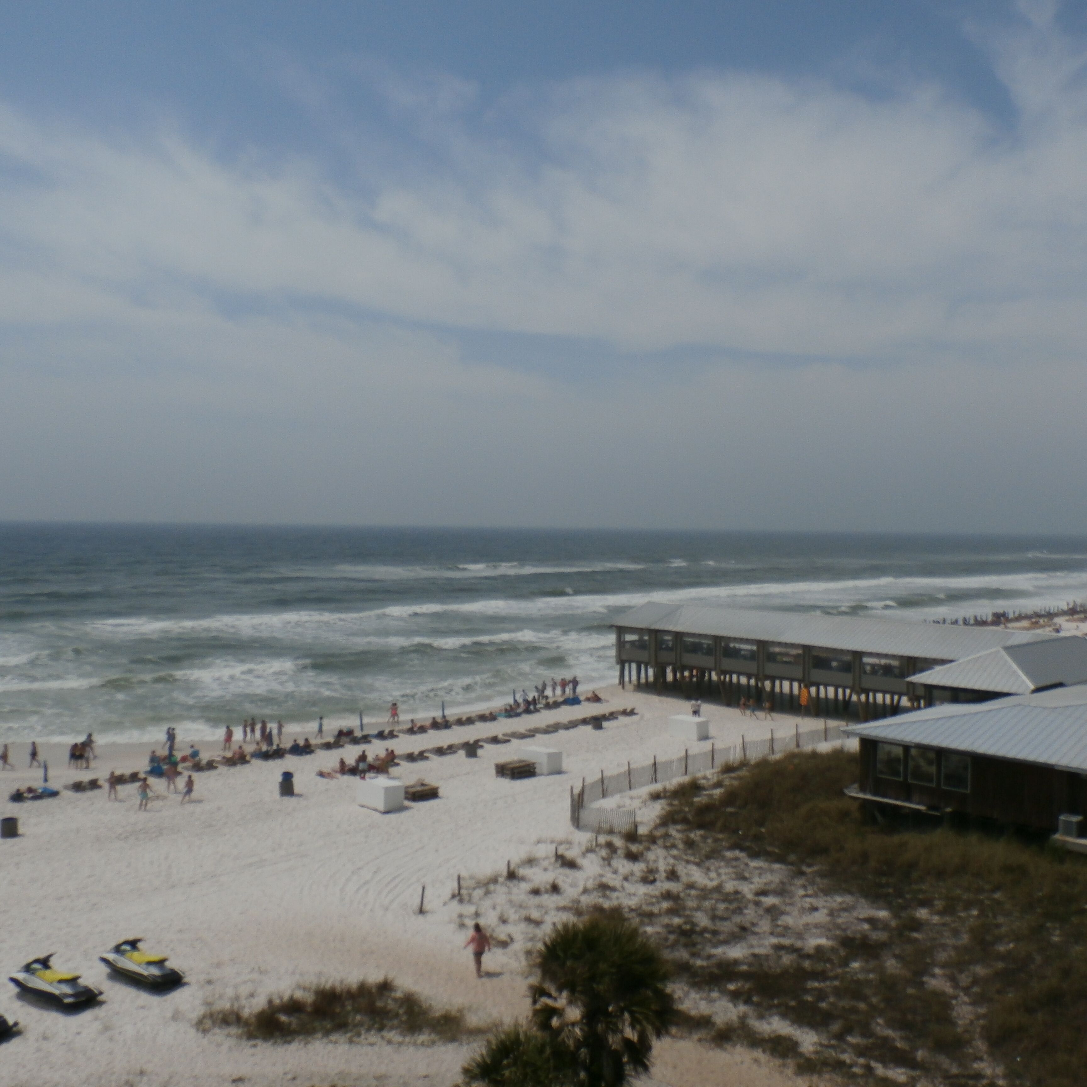 A beach with a wooden pier, sandy beach, and ocean view.
