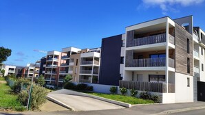 Un complejo moderno de apartamentos con varios balcones y un cielo azul despejado.