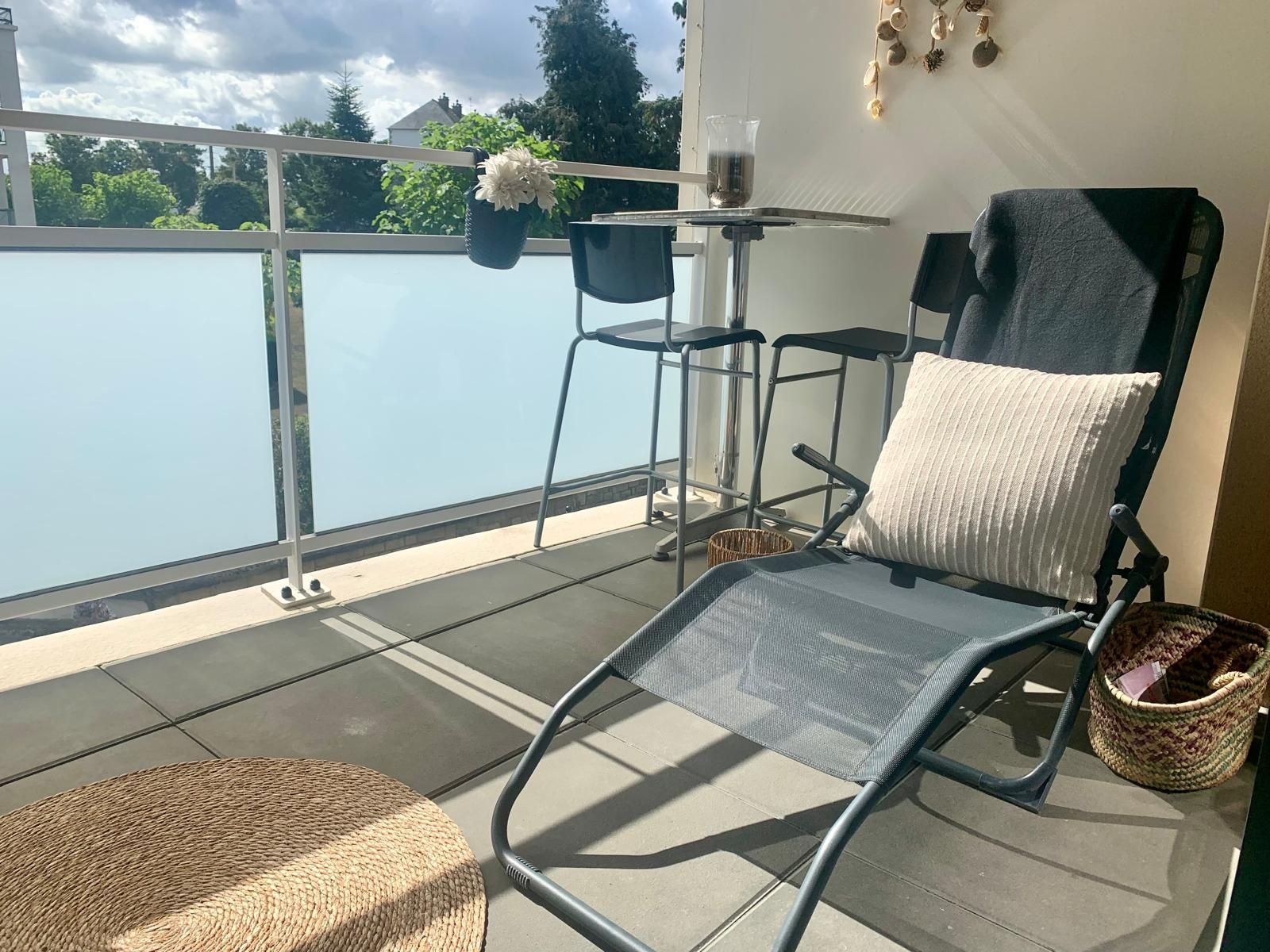 A balcony with a chair, a small table, and a potted plant.