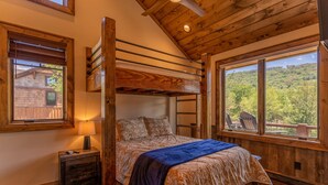 Una cama individual con vistas a una zona boscosa, un cabecero de madera y una mesita de noche con lámpara.