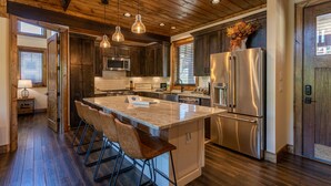 Una cocina amplia con una isla grande, electrodomésticos de acero inoxidable y detalles de madera.