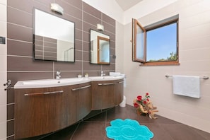 A modern bathroom with two sinks, a large mirror, and a window.