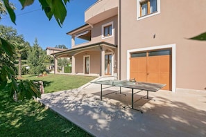 A two-story house with a covered patio area featuring a ping pong table.