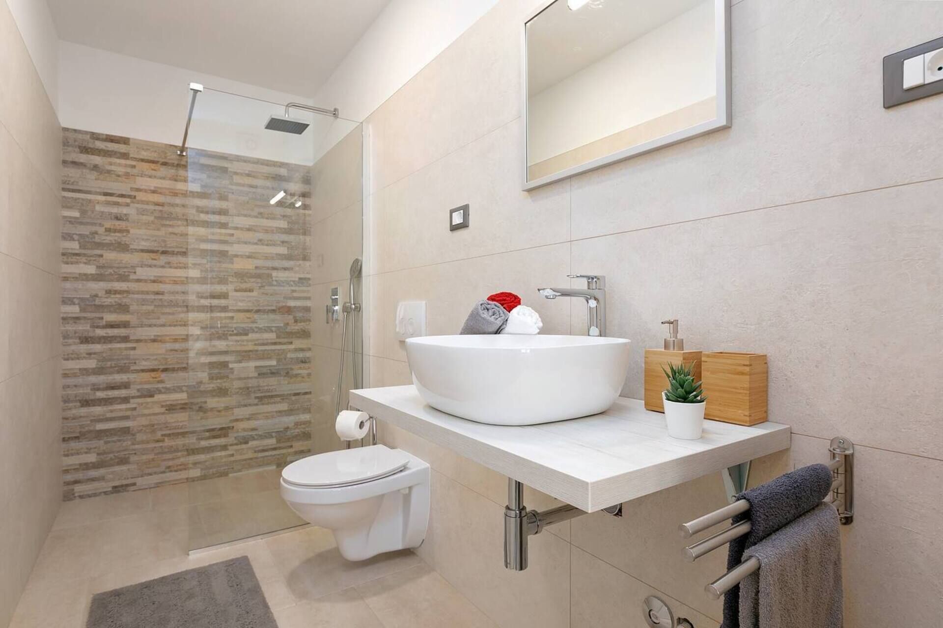 A modern bathroom with a glass-enclosed shower, a white sink with a wooden soap dispenser, and a toilet.