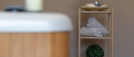 A wooden shelf with towels and a small plant.