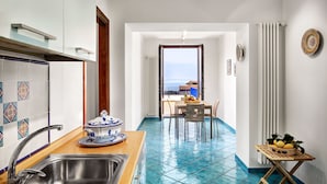 Una cocina con un lavamanos, una zona de comedor con mesa y sillas, y una vista a través de una puerta abierta.