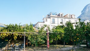Un edificio con balcón, rodeado de árboles y una montaña al fondo.