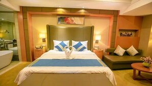 A hotel room with a large bed, a sofa, a small table, and a bathroom visible through an open door. - Boyue Hotel (Changchun)