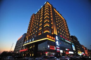 A multi-story hotel with illuminated signage and a modern architectural design. - Boyue Hotel (Changchun)