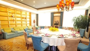 A dining area with a round table set for six, surrounded by blue upholstered chairs. - Boyue Hotel (Changchun)