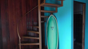 A spiral staircase with a surfboard leaning against a blue wall.