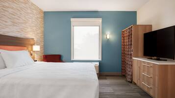 A hotel room with a bed, a TV, a wardrobe, and a window.