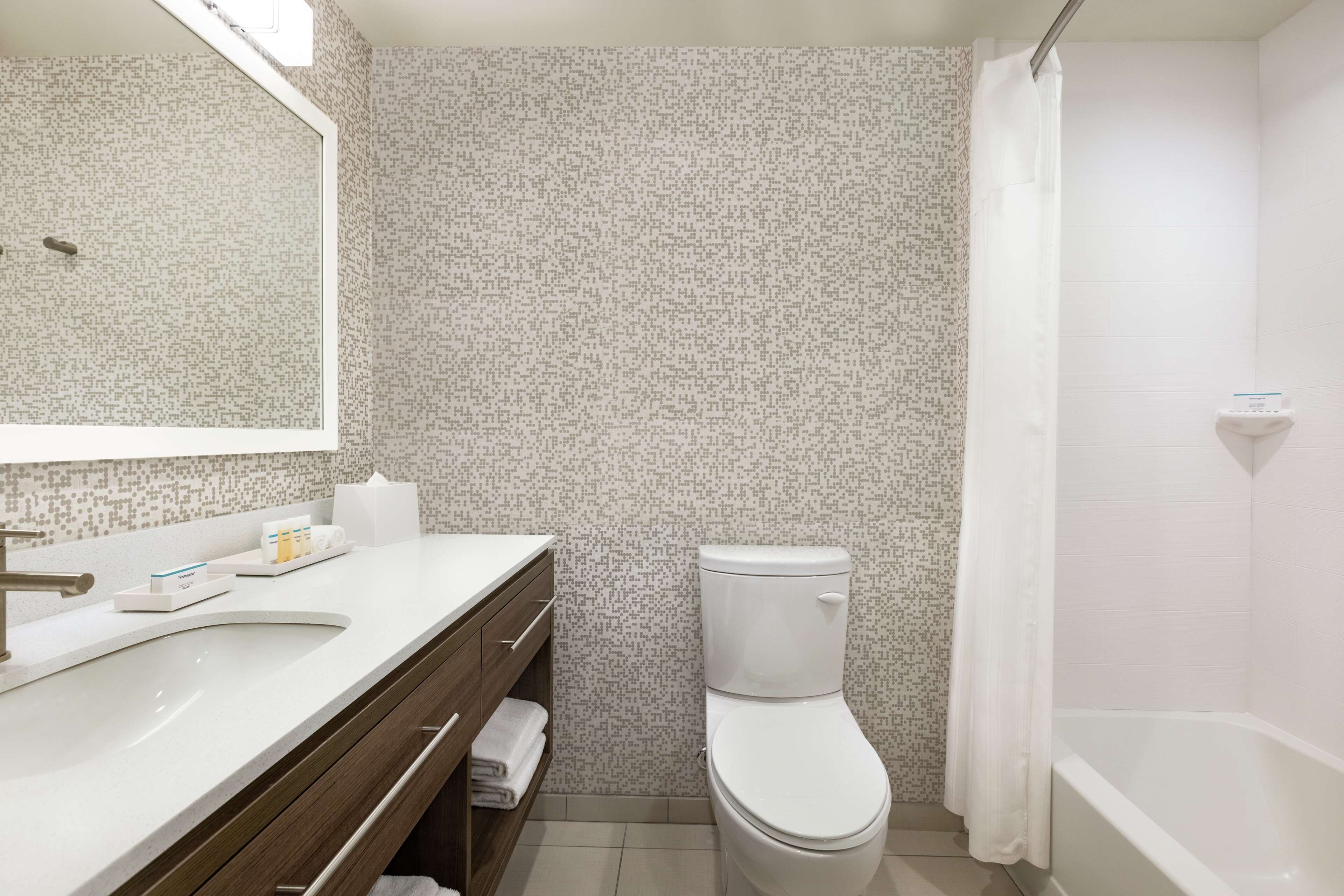 Un baño con lavamanos, tocador, inodoro y bañera blancos.