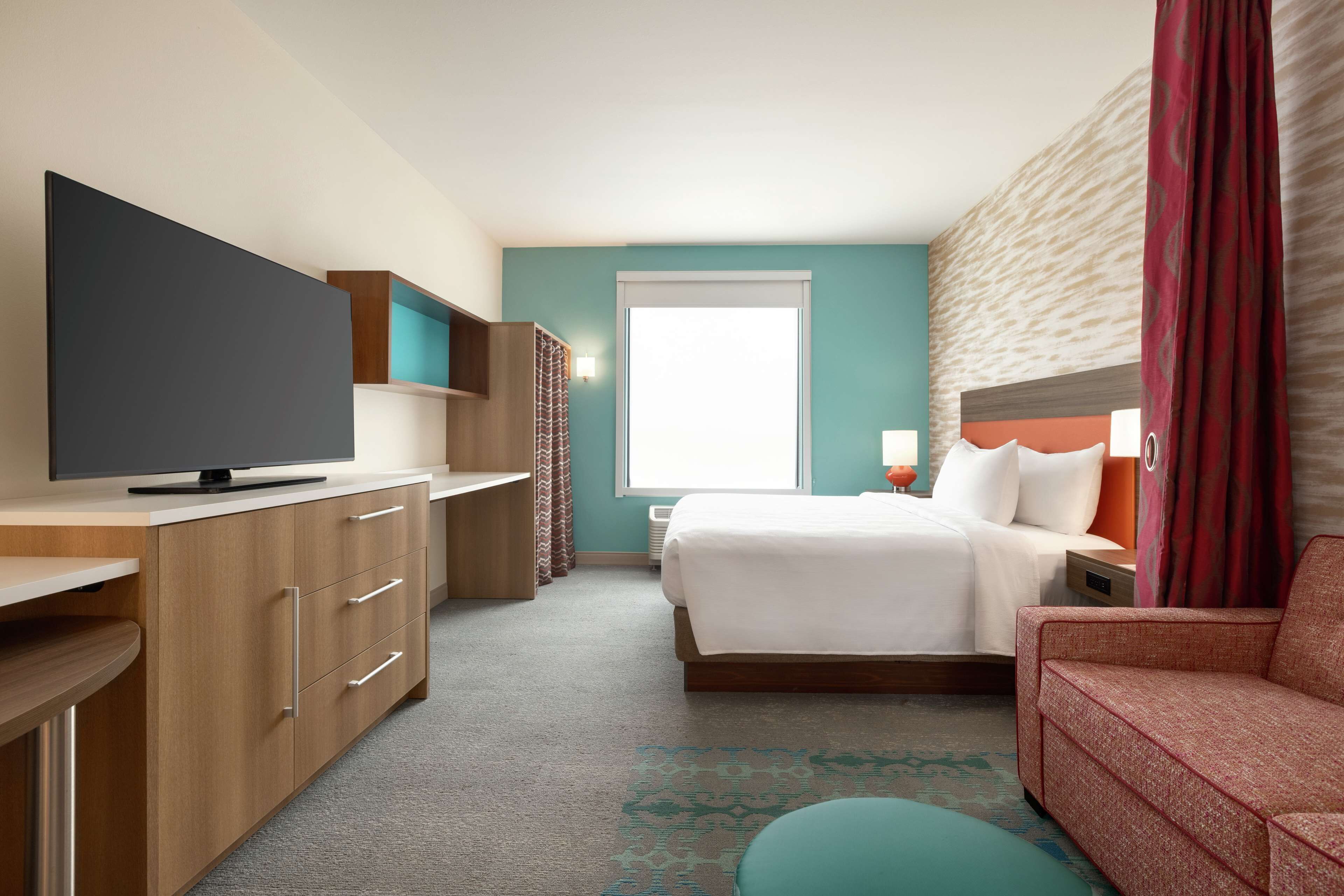 Ein Hotelzimmer mit Bett, Fernseher, Schreibtisch und einer Couch.