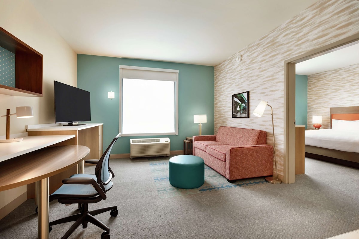 A hotel room with a desk, chair, sofa, and a bed.