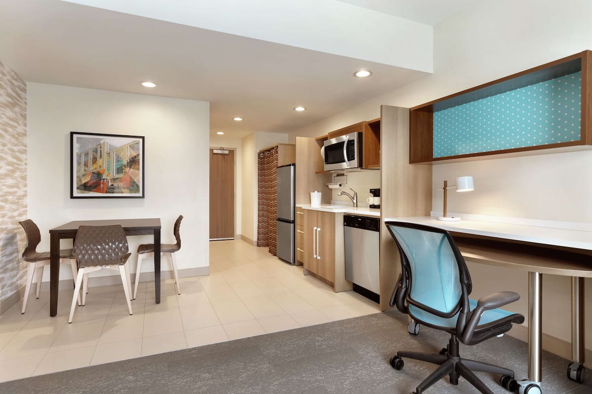 A modern kitchen with a dining area, a microwave, and a refrigerator.