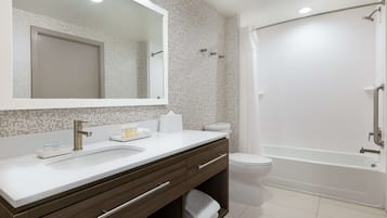 Un baño moderno con un lavabo blanco, un espejo grande, un inodoro y una bañera.
