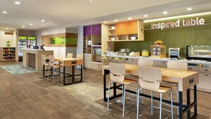 A modern restaurant with a long counter, multiple seating areas, and a visible menu board. - Home2 Suites by Hilton New Brunswick, NJ (New Brunswick)