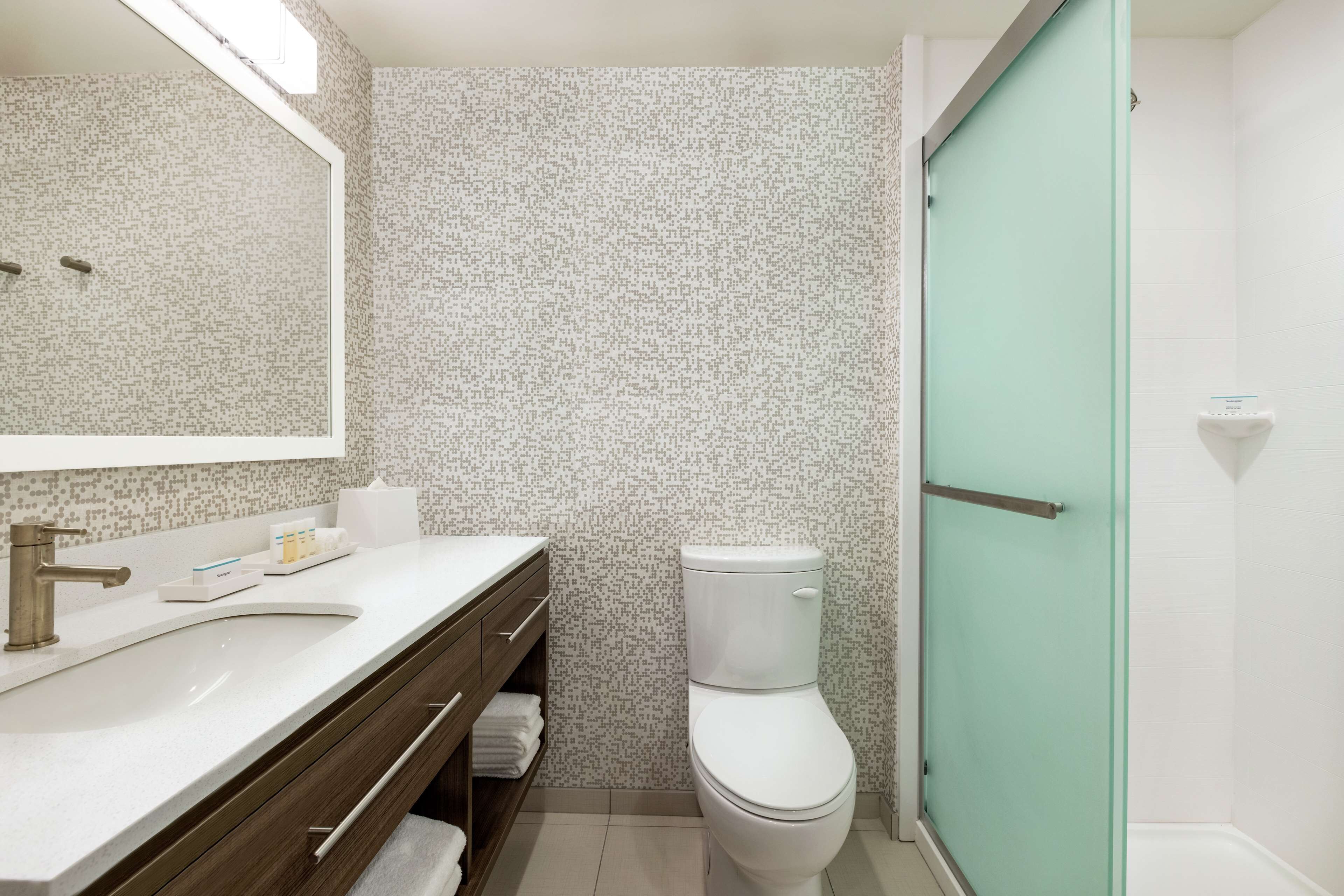 Un baño con un lavamanos blanco, un espejo, un inodoro y una zona de ducha.