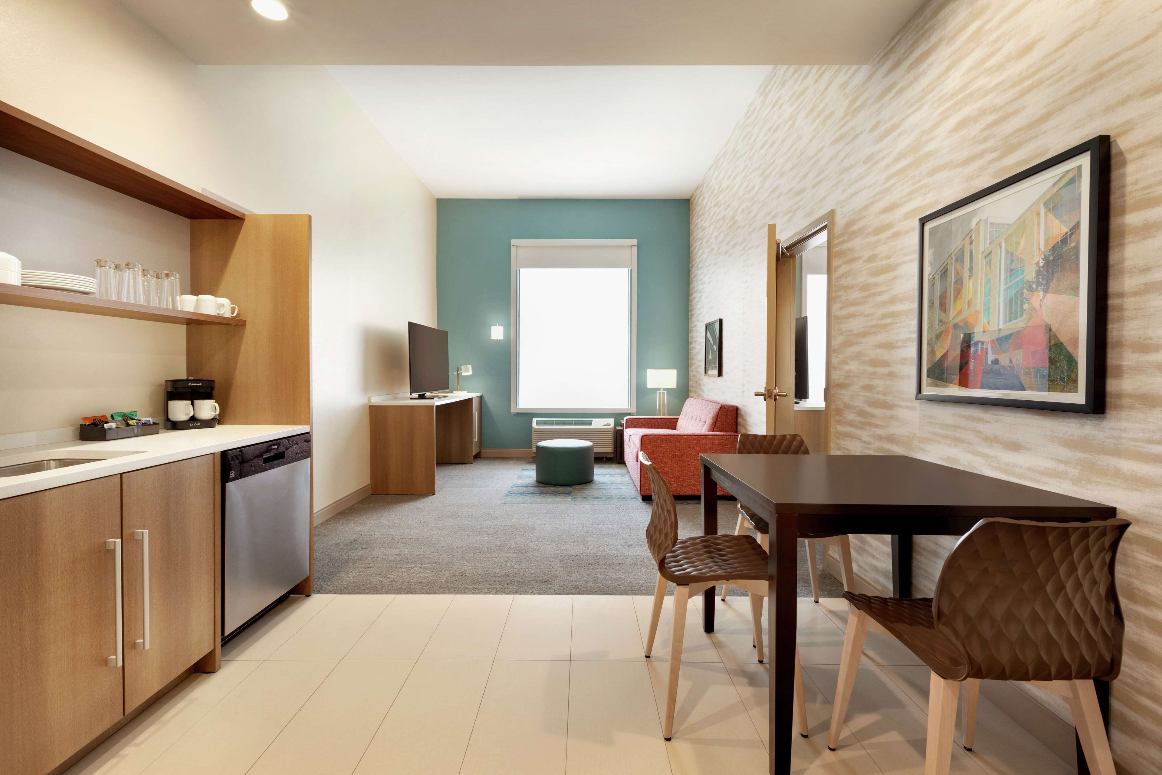 A modern kitchen with wooden cabinets, a dishwasher, and a dining area with two chairs and a table.
