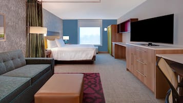 Una habitación de hotel con cama, sofá, escritorio, televisor y ventana.