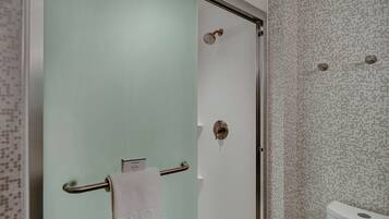 Un baño con puerta de vidrio, ducha e inodoro.