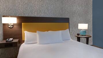 A neatly made bed with white linens, a wooden headboard, and two bedside tables with lamps.