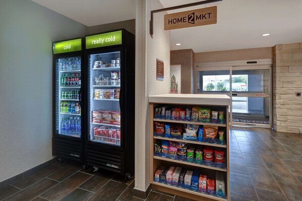 A vending area with two refrigerated beverage dispensers labeled "cold" and "really cold," and a shelf stocked with snacks and beverages. - Home2 Suites by Hilton East Hanover (East Hanover)