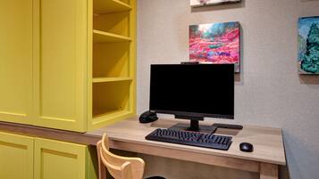 A computer desk with a monitor, keyboard, and mouse. There are yellow cabinets and a chair.