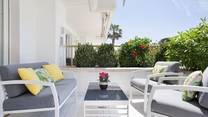 A patio with white furniture, a table, and potted plants.